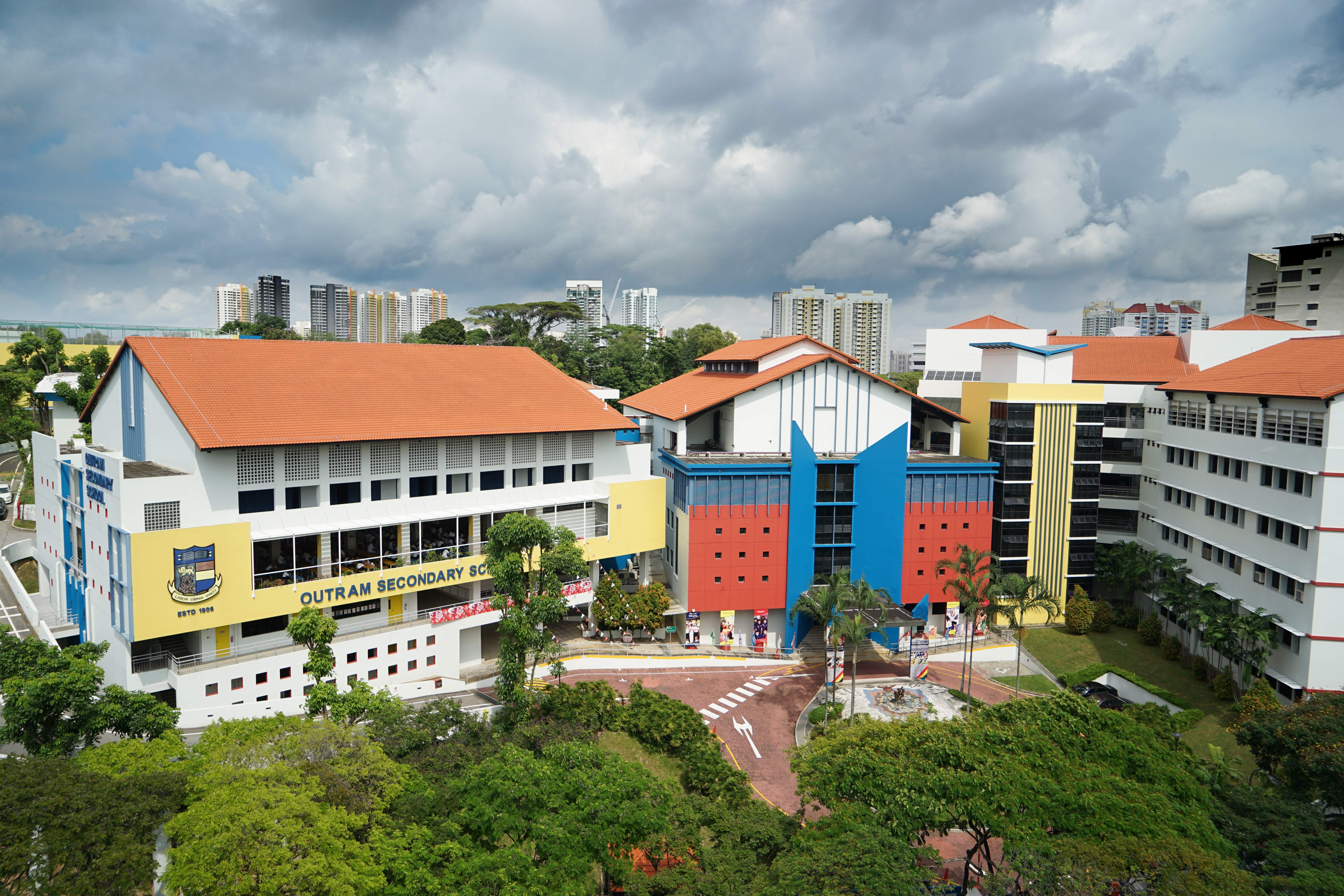Aerial view of Outram Secondary School campus with colorful red, blue, and yellow buildings and orange rooftops.